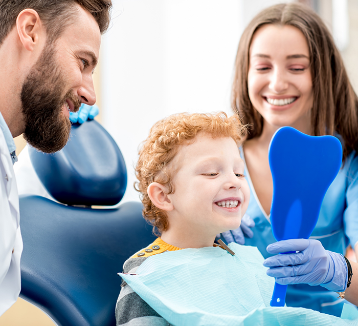 Young boy looking at his smile in a mirror while visiting dental office in San Antonio