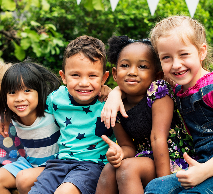 Four kids smiling outdoors after seeing their childrens dentist in San Antonio