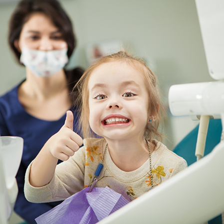 Young girl giving a thumbs up in the dental chair