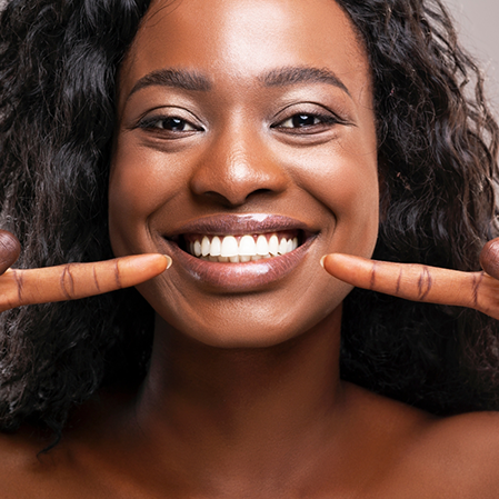 Smiling woman pointing to her flawless teeth