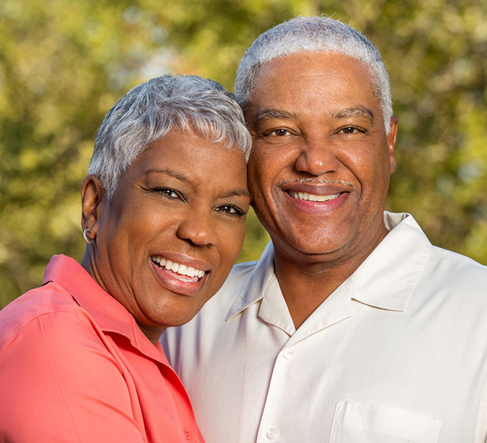 Senior man and woman smiling outdoors together with dental implants in San Antonio