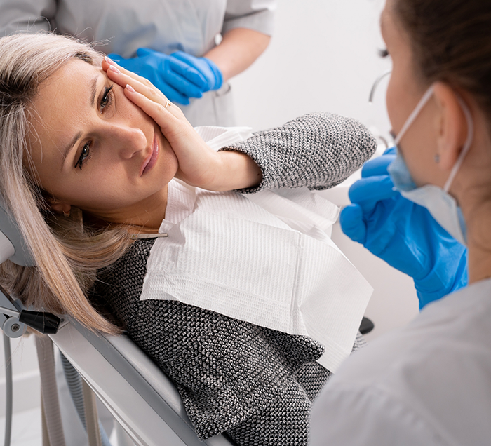 Woman holding her cheek in pain while visiting her emergency dentist in San Antonio