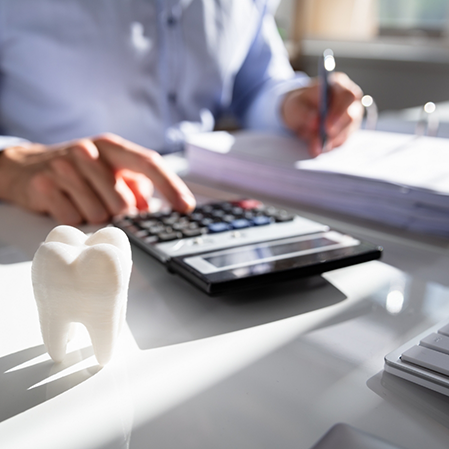 Person filling out paperwork while typing on a calculator