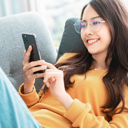 Young woman smiling while scrolling on her phone