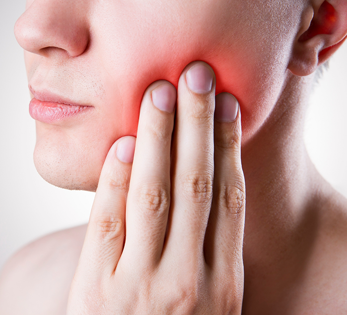 Person holding their cheek in pain before root canal treatment in San Antonio